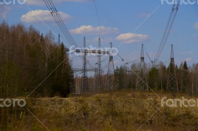 High voltage power lines against the blue sky and the spring for