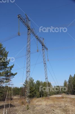 High voltage power lines against the blue sky and the spring for