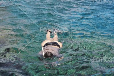 Woman photographer diving into water of Red sea