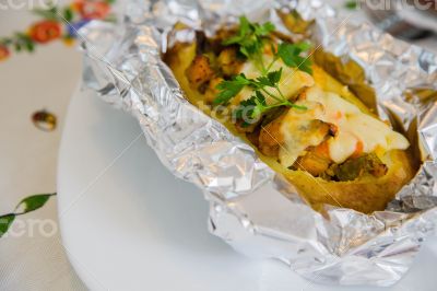 Baked potato with vegetables,chicken filet,fresh parsley and che