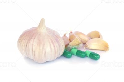 Herbal pills and garlic on a light colored background