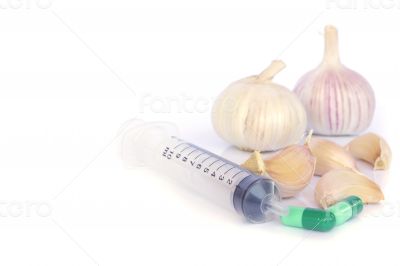 Herbal pills and garlic on a light colored background