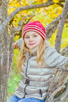 Cute girl in autumn sit on tree
