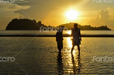 Girls and boy on the beach during sunrise