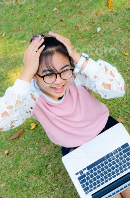 Cute girl is happy with notebook on grass