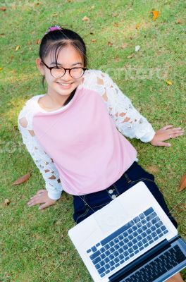 Cute girl is happy with notebook on grass
