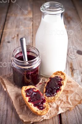 black currant jam in glass jar, milk and crackers 