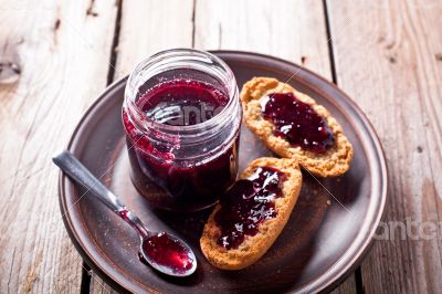 black currant jam in glass jar and crackers