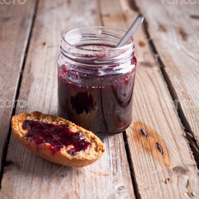 black currant jam in glass jar and cracker