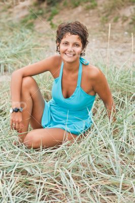 brunet woman in blue sitting in a grass