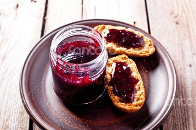 black currant jam in glass jar and crackers 