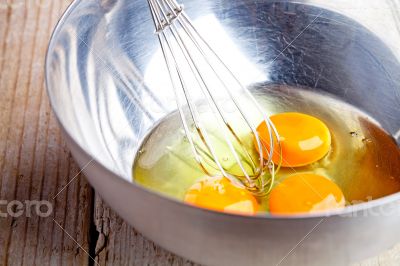 whisking eggs in metal bowl 