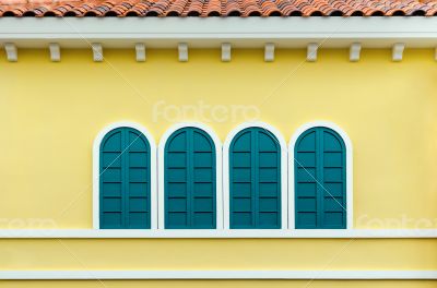 Four green arched windows on yellow wall