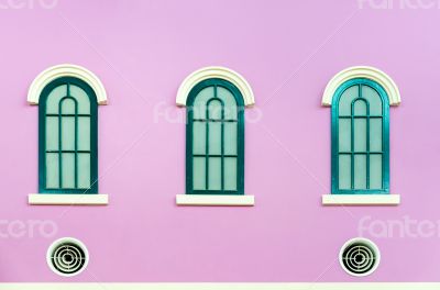 Three green arched windows on pink wall