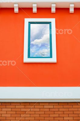 Sky reflection in window glass on orange wall