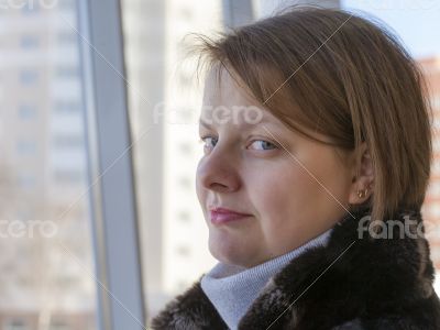 The young woman looks out of the big window