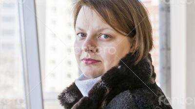 The young woman looks out of the big window