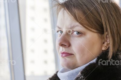 The young woman looks out of the big window