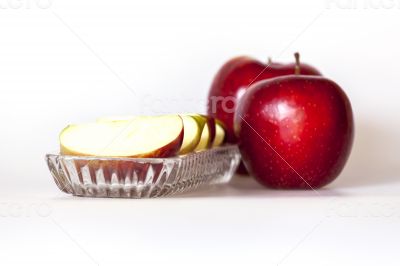 Two ripe red apples and segments of apple on a plate