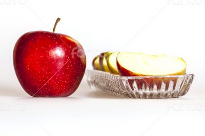Ripe red apple and segments of apple on a plate