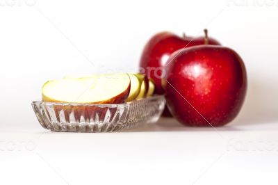 Two ripe red apples and segments of apple on a plate