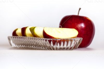Ripe red apple and segments of apple on a plate