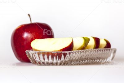 Ripe red apple and segments of apple on a plate