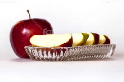 Ripe red apple and segments of apple on a plate