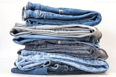 Pile of jeans of various colors on a counter in shop