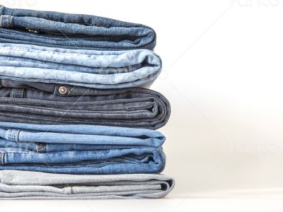Pile of jeans of various colors on a counter in shop