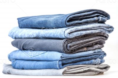 Pile of jeans of various colors on a counter in shop