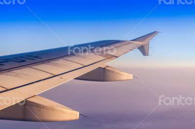 Flight at sunrise. The wing of the plane