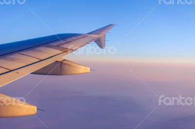 Flight at sunrise. The wing of the plane