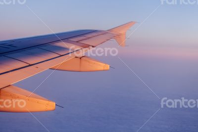 Flight at sunrise. The wing of the plane