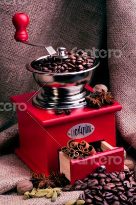 Red coffee grinder on a sackcloth background