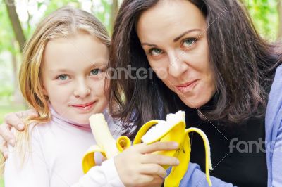 Mother and daughter eating banana