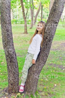 Cute girl in summer sit on tree