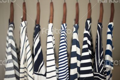 A row of navy striped tops for women on wooden hangers in a clos