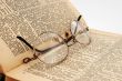 The opened old dictionary with glasses
