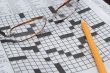 reading glasses and a pencil on a crossword puzzle