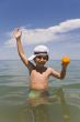 The boy with an orange on a background of the sea