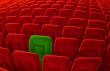 One green chair among many red seatings