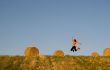Woman jumping in a hay bales field