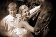 Groom and bride holding a brown horse