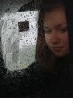 Girl looks thru waterdropped widow glass