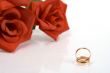 Two wedding rings and red rose at the background