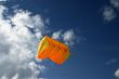 Orange kite next to the clouds