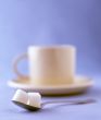 two sugar cubes with a cup of coffee on a saucer