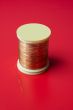 bobbin of golden thread on a red background