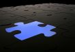 blue puzzle piece amongst black pieces